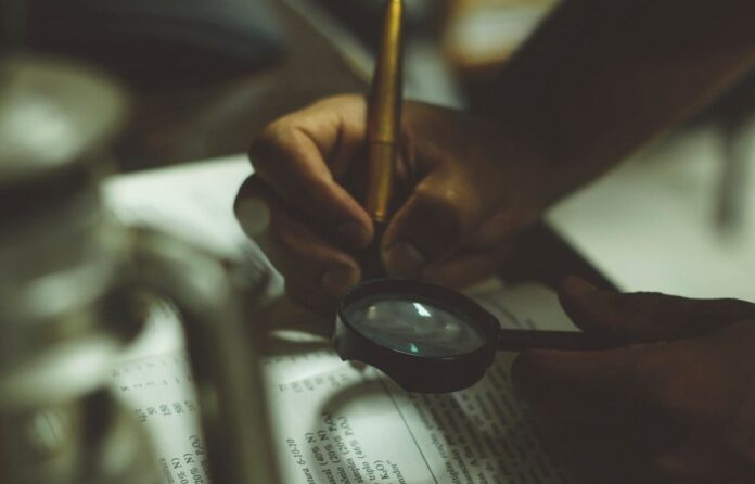 Man analyzing papers with a magnifying glass