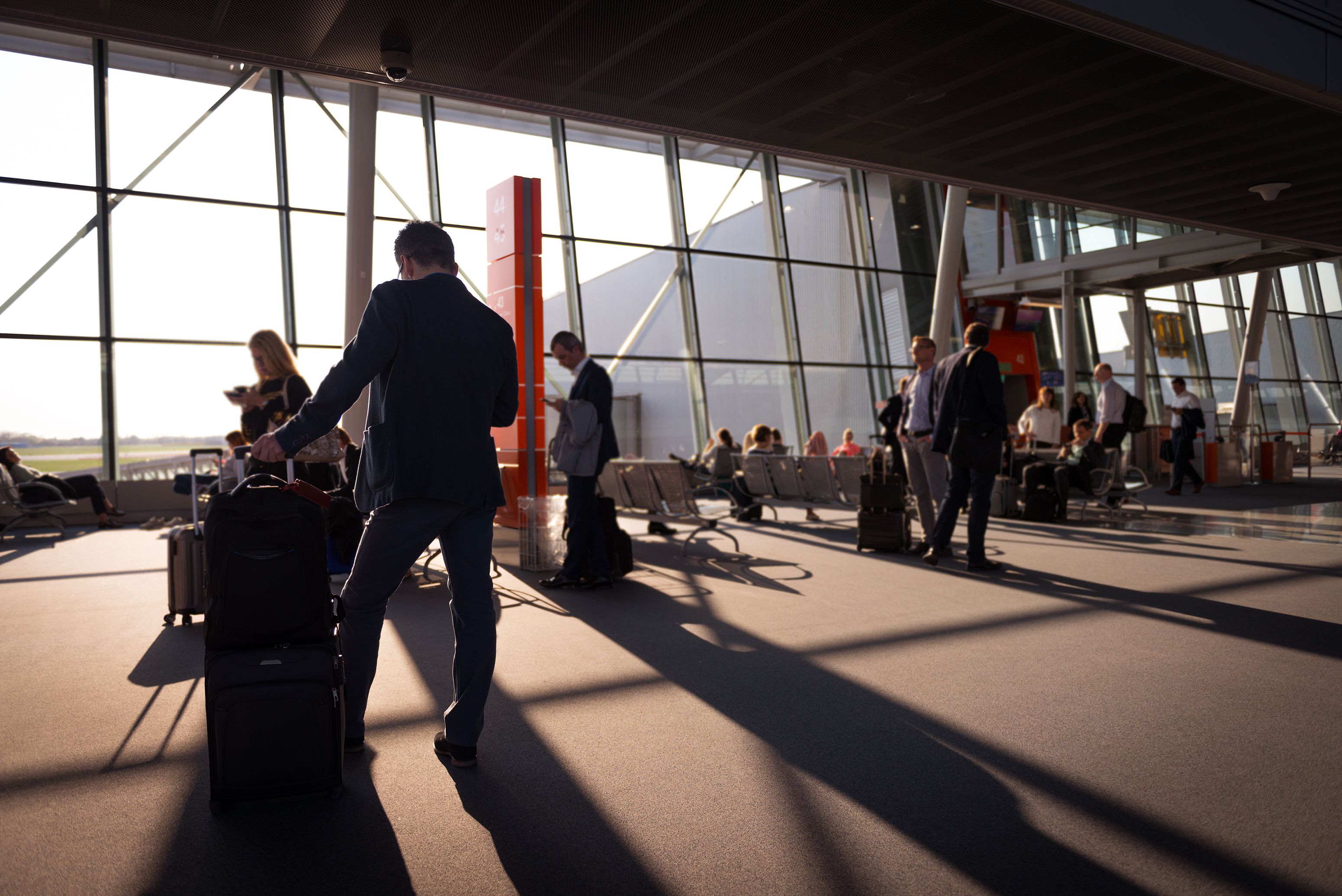 Travelers with luggage in an airport terminal heading to their procedure abroad
